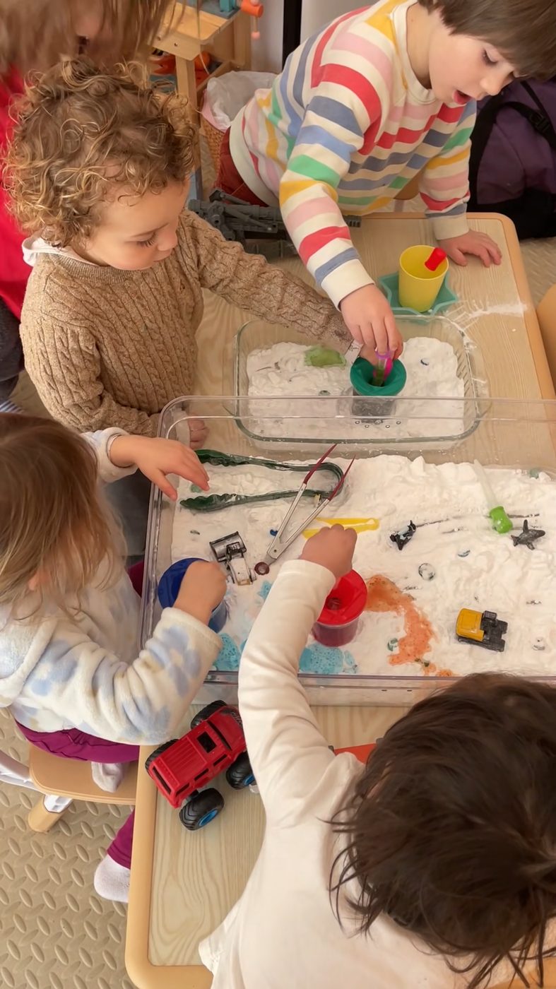 Four children investigate fizzing snow-science bins together