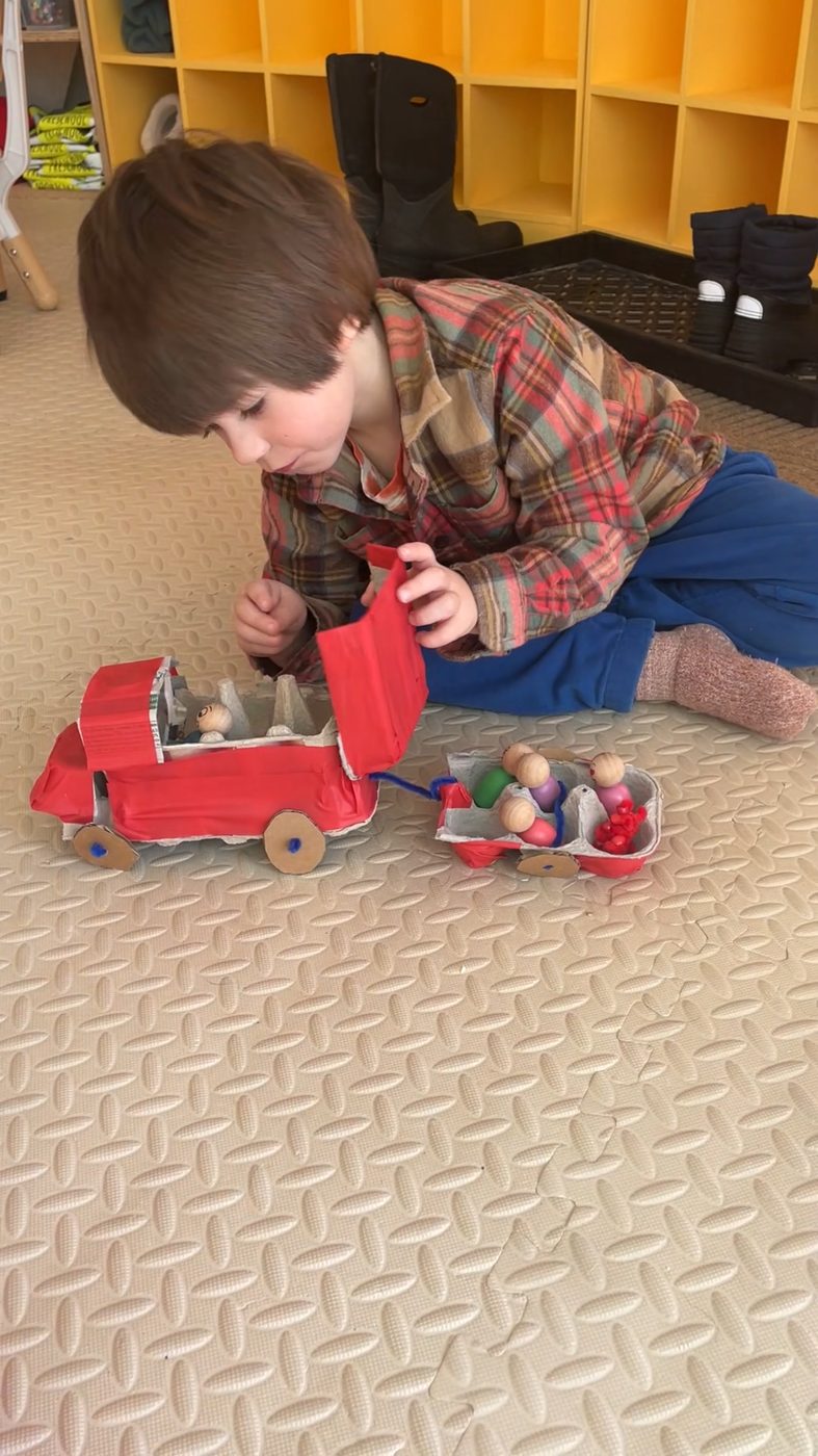 A child plays with the egg-carton truck and peg people he built